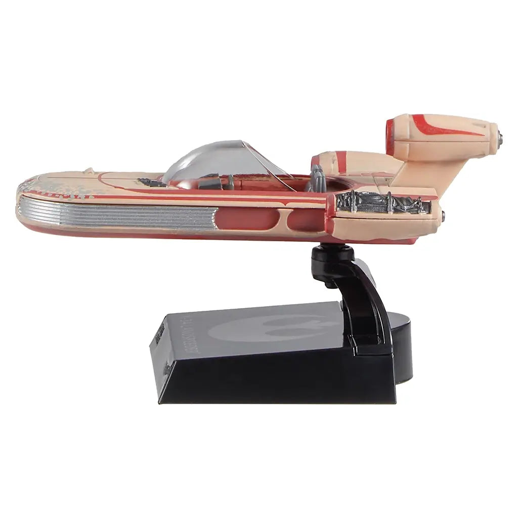 Hot Wheels Star Wars X-34 Landspeeder side profile highlighting the long streamlined body, tan plastic hull with red markings, ribbed side panels, and elevated display stand designed for shelf presentation.