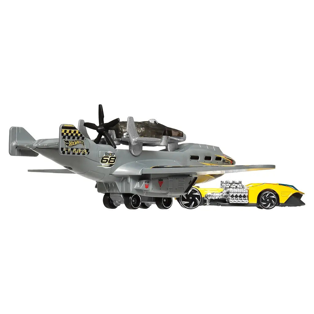 Hot Wheels Turbulence Tug rear angled view highlighting the gray aircraft tail section, black propellers, wing structure, rolling wheels, and the yellow race car positioned below on white.