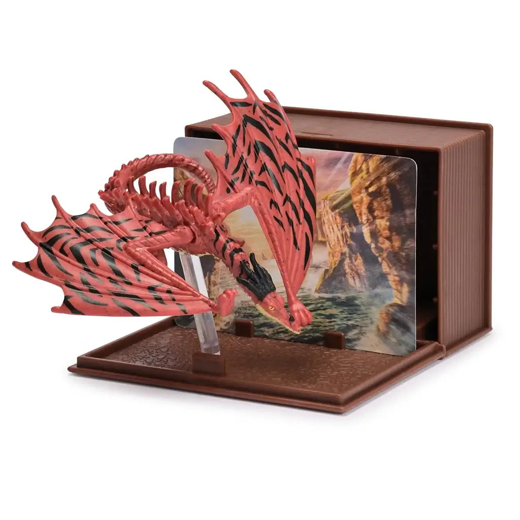 How to Train Your Dragon Deadly Nadder dragon figure in red and black plastic with spiked wings and curled tail, posed on a stand with canyon background inside a brown book style display case.