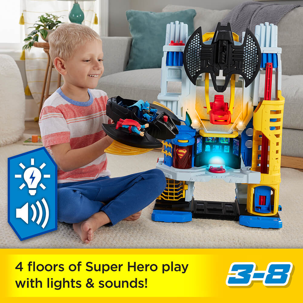 Picture of a boy playing with the Imaginext DC Super Friends Ultimate Headquarters Hall of Justice Playset with working that says there are 4 floors of super hero play with lights and sounds for ages 3-8 years old