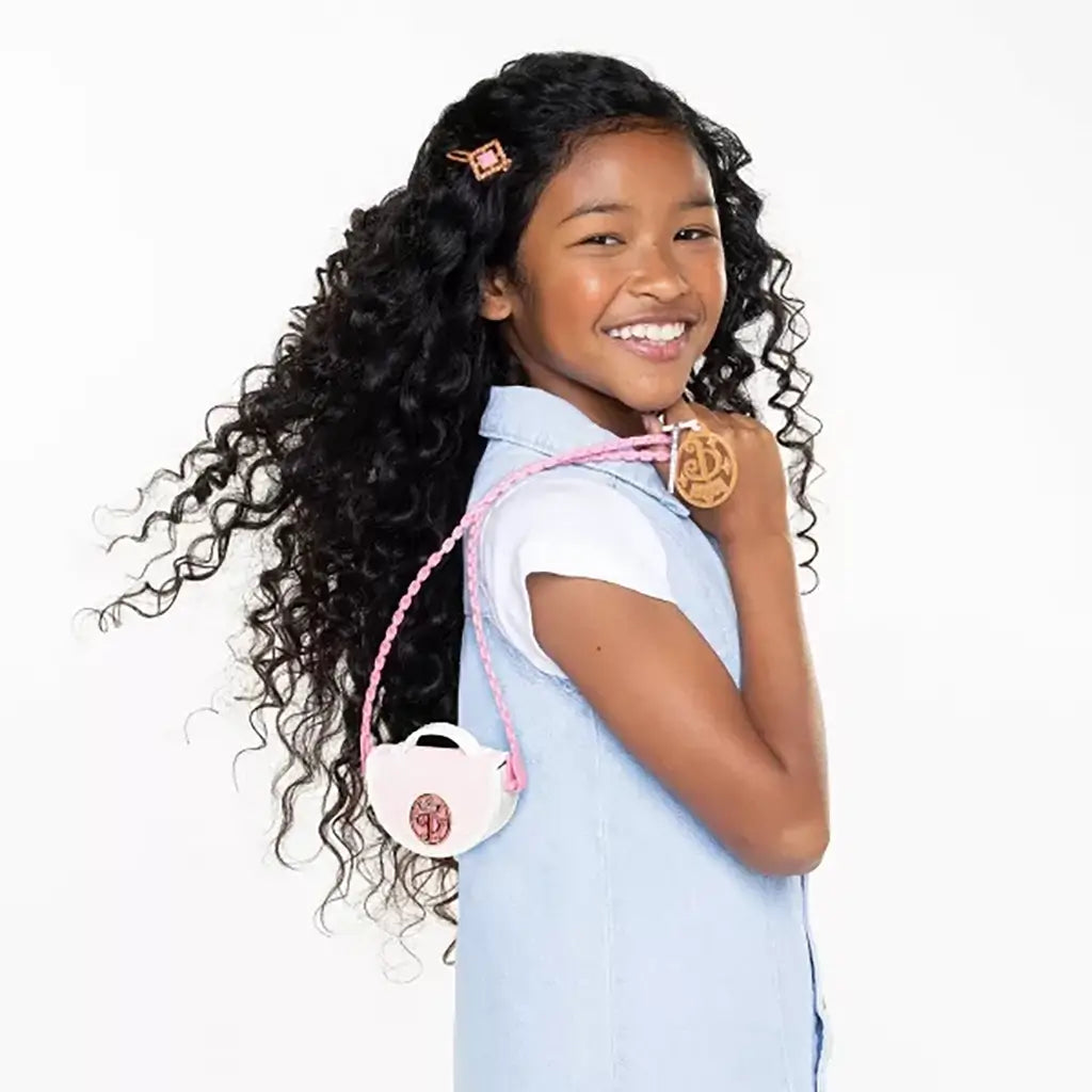 Smiling child holding a Disney Princess Style Chic Petites mini purse with pink strap over shoulder, showing playful fashion pretend activity.