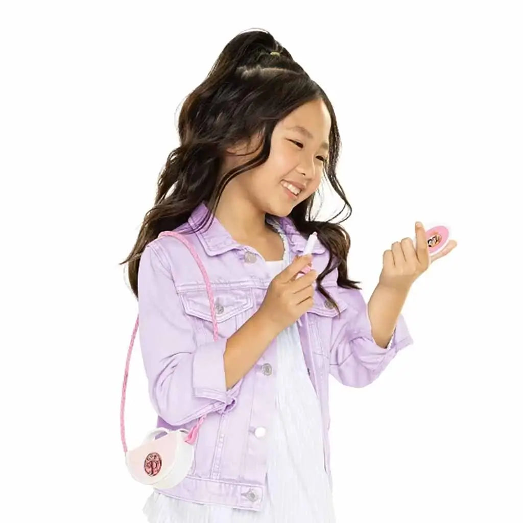Smiling child wearing lavender jacket using Disney Princess Style Chic Petites makeup accessories, demonstrating creative roleplay fun.