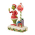 Angled front view of Jim Shore LED figurine featuring Grinch in Santa coat next to red stop sign reading "STOP LEAVE PRESENTS HERE" with bright gift decorations.