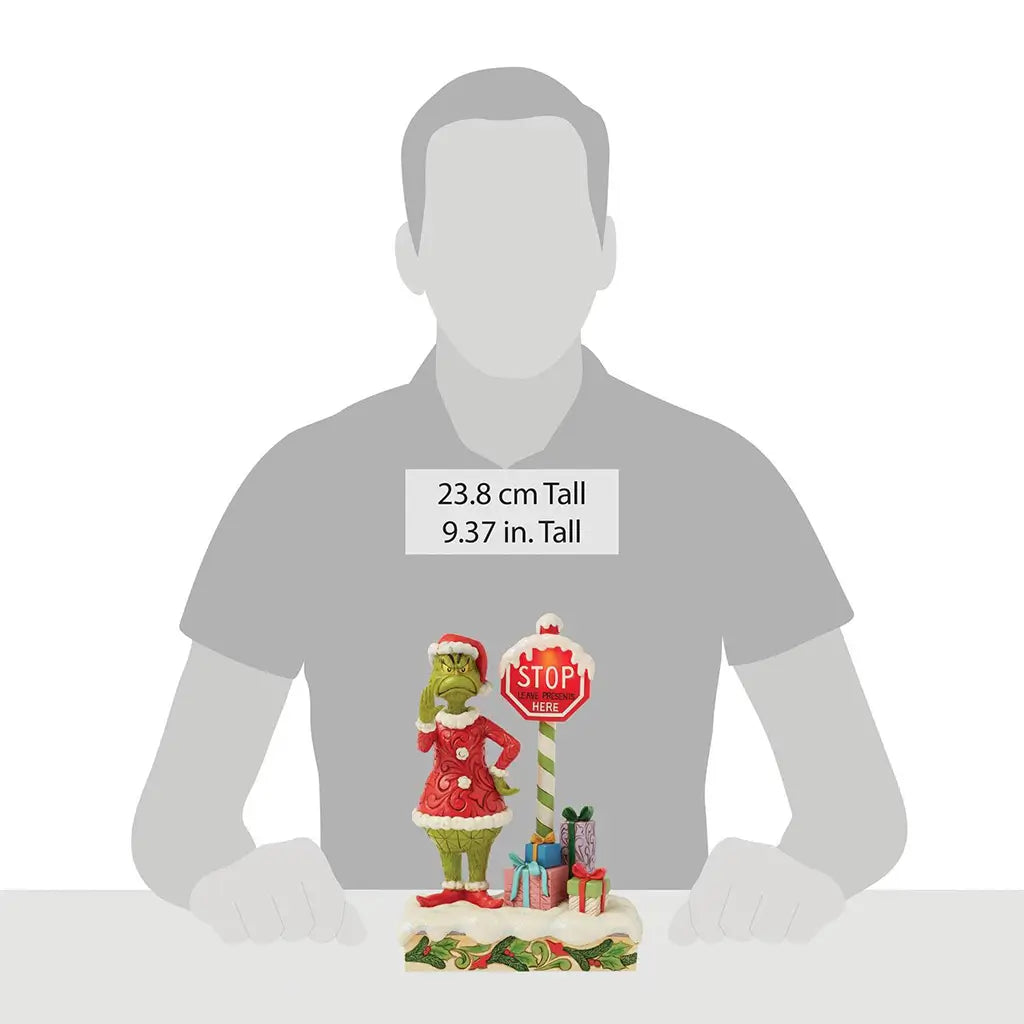 Size comparison image showing 9.37-inch tall Jim Shore Grinch figurine with LED stop sign and presents, placed before silhouette hands for scale reference.