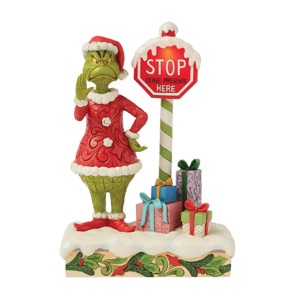 Full front view of Grinch figurine by Jim Shore featuring light-up stop sign, snow-covered base, and festive presents around the Grinch in Santa attire.