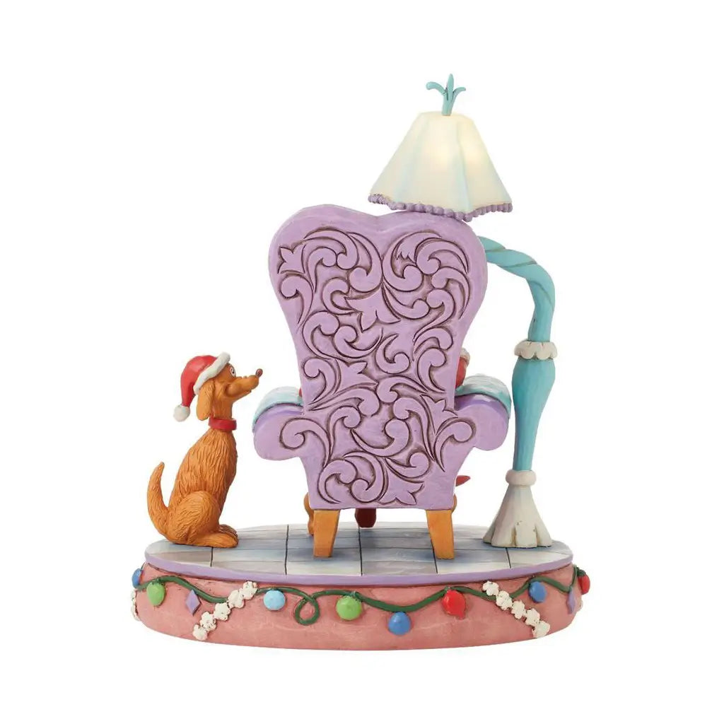 Rear view of Jim Shore Grinch LED figurine showing purple ornate chair, glowing lamp, and Max the dog in a Santa hat on a Christmas-themed base.