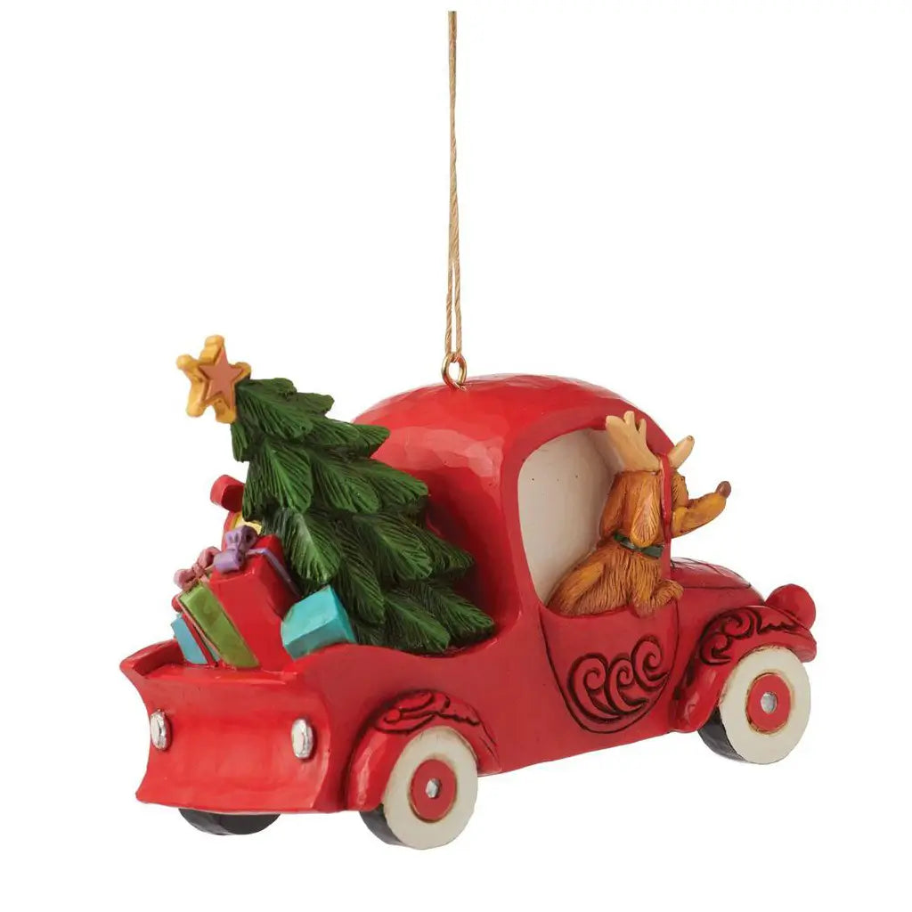 Rear angle view of Jim Shore ornament featuring Max driving a red vintage truck with a Christmas tree and gifts in the back, sculpted in festive detail.