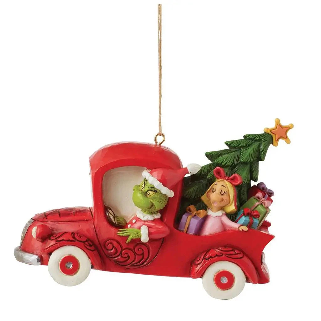 Side view of Jim Shore red truck ornament with Max in the front seat and a loaded bed with a Christmas tree and colorful presents.