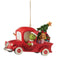 Full side view of Jim Shore ornament with Grinch driving a red Christmas truck, Cindy Lou Who sitting beside gifts and a tree in the back.