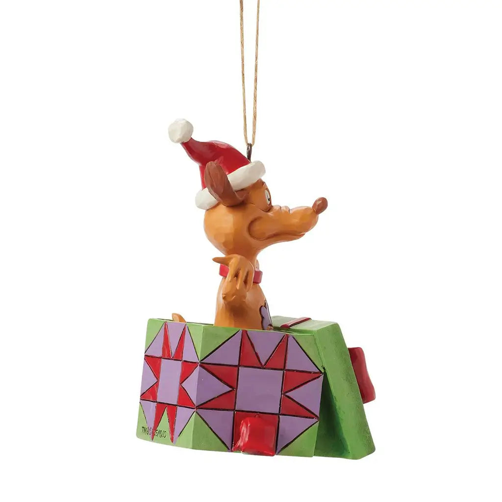 Side view of Jim Shore Max Christmas ornament showing the dog in a Santa hat emerging from a patterned green and purple gift box with a red bow.