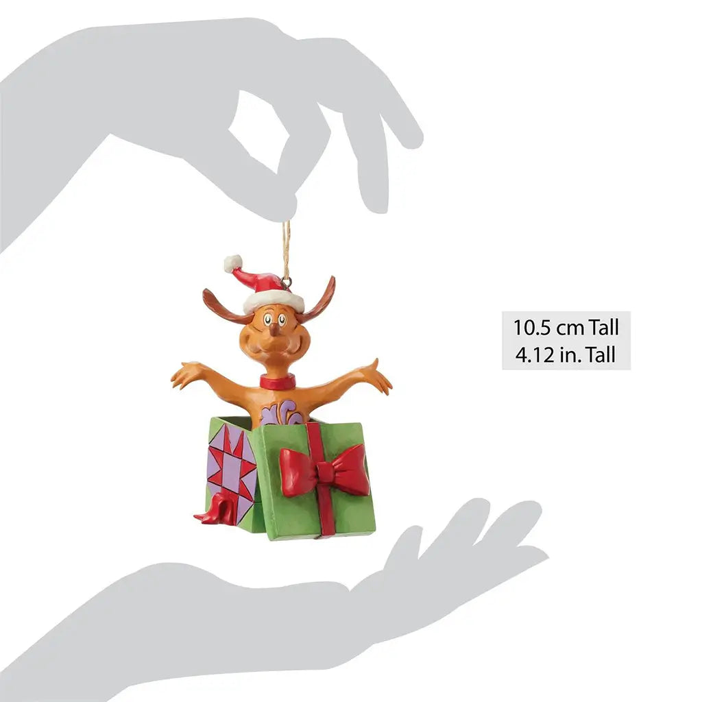 Size comparison image showing 4.12-inch Jim Shore Max ornament in a Santa hat popping out of a gift box, held between two hands for scale reference.