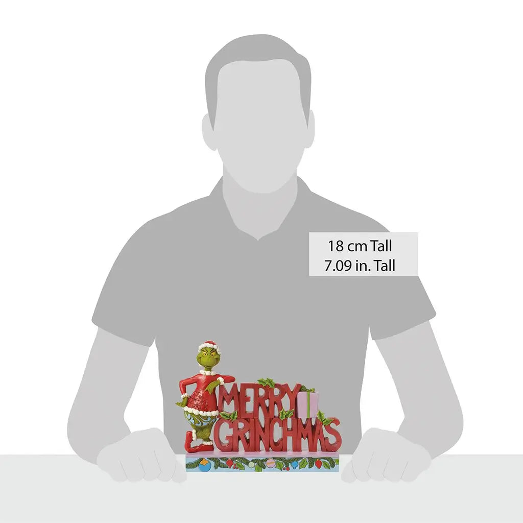Size comparison image of Jim Shore "Merry Grinchmas" figurine featuring the Grinch beside large red holiday letters, standing 7.09 inches tall.