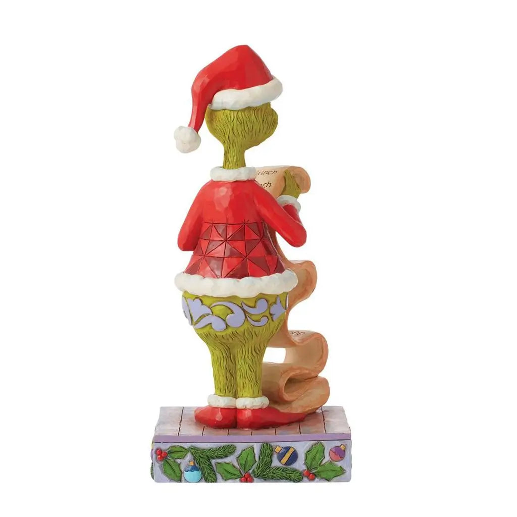 Rear view of Jim Shore Grinch figurine wearing red Santa jacket and holding a curled name list, standing on a holiday base with holly and ornament design.