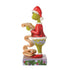Alternate side view of Jim Shore Grinch figurine in Santa attire, reading a curled name list, on a purple holiday base with evergreen and ornament accents.