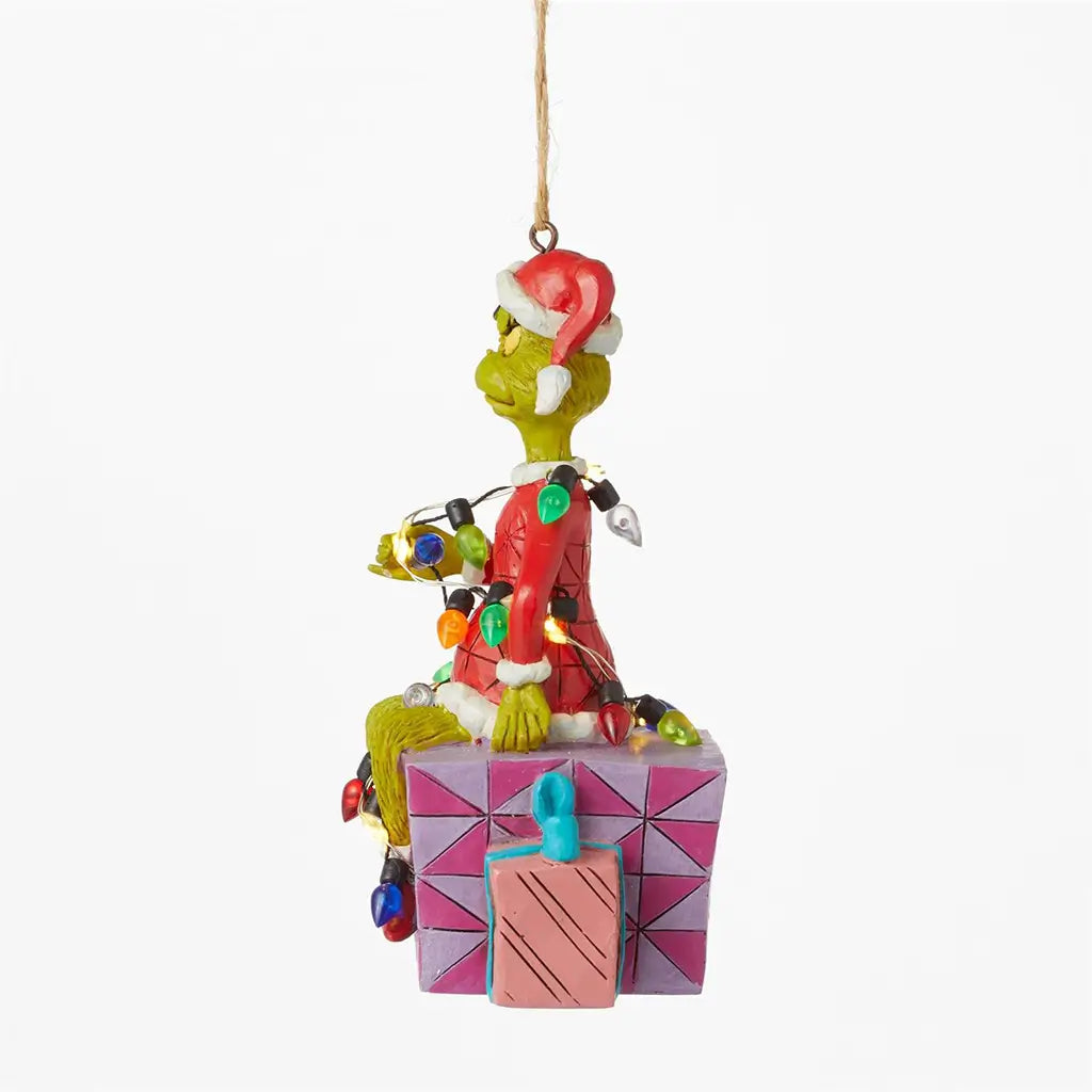 Alternate side view of Jim Shore Grinch ornament, showing Grinch wrapped in lights while sitting on a decorated gift box with visible pink and teal presents.