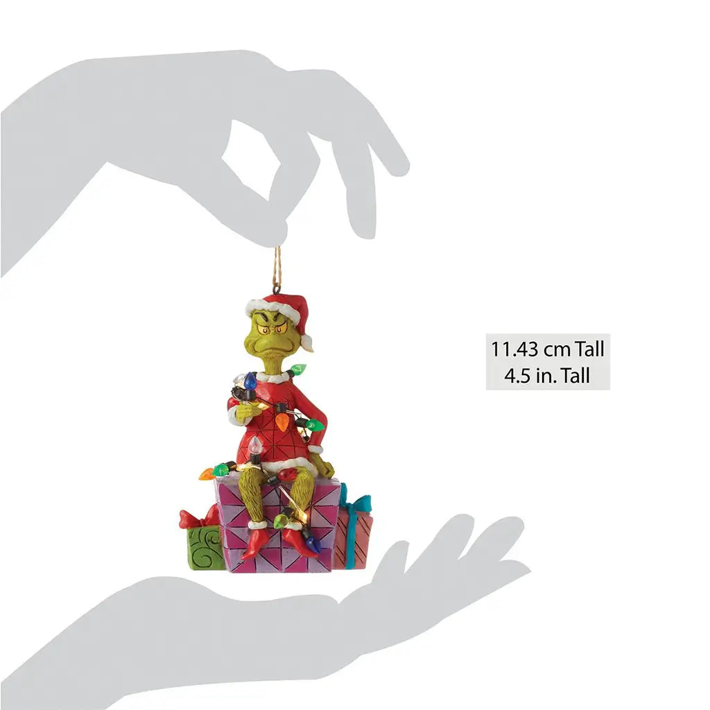 Size comparison image of Jim Shore Grinch ornament, 4.5 inches tall, shown being held by a silhouette hand, featuring Grinch wrapped in lights on a gift box.