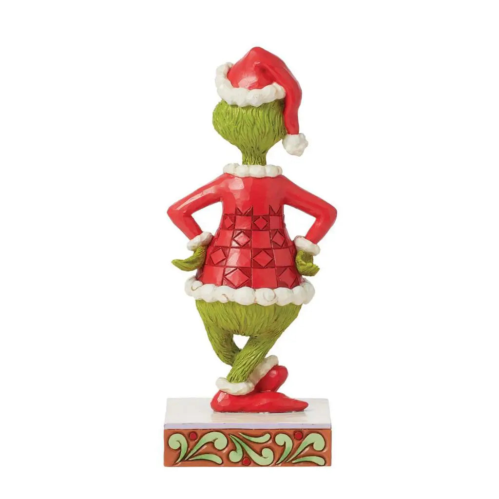 Rear view of Grinch figurine wearing red Santa coat and hat, arms akimbo on decorated base; part of Jim Shore’s Christmas collectible series.