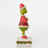Side view of a 6-inch Jim Shore Grinch figurine wearing a Santa outfit with red coat, green legs, and festive patterns, standing on a decorative base.