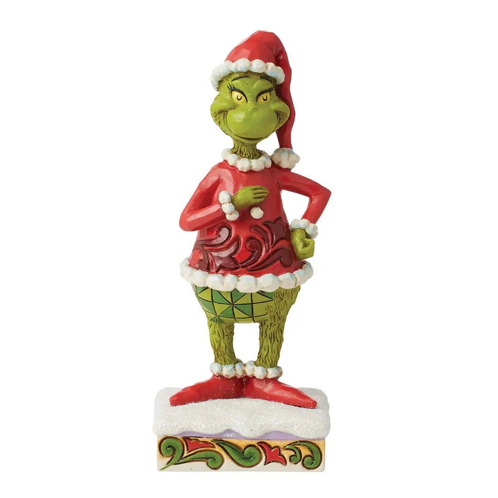 Front view of a 6-inch Jim Shore Grinch figurine in a red Santa outfit, smiling with one hand on hip, standing on a snow-like base with holiday accents.