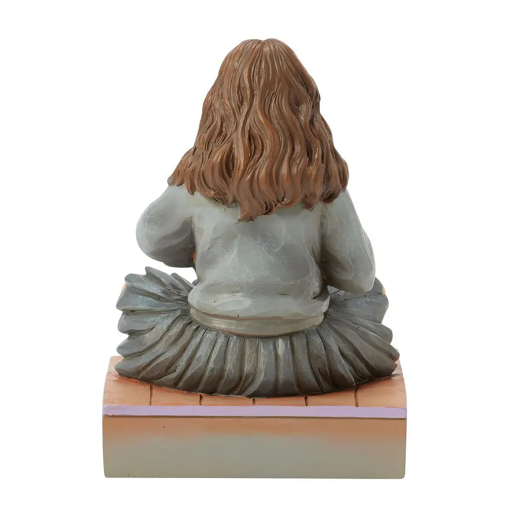 Rear view of Jim Shore Hermione figurine highlighting textured brown hair, grey pleated skirt, and hand-carved look with painted shading across the back of her robes.