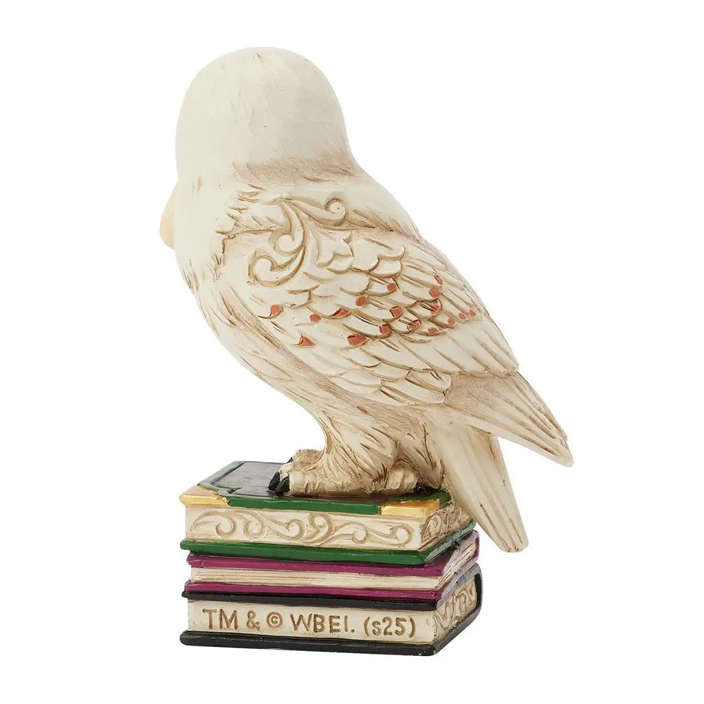 Rear view of Jim Shore Hedwig figurine highlights textured feather design, carved accents, and stacked book pedestal supporting the snowy owl.
