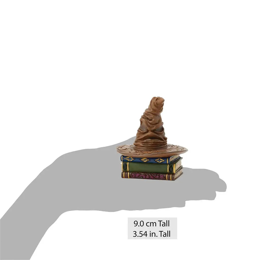 Jim Shore Sorting Hat mini figurine measures 9 cm tall, featuring wrinkled brown hat atop sculpted book stack with vibrant painted designs.