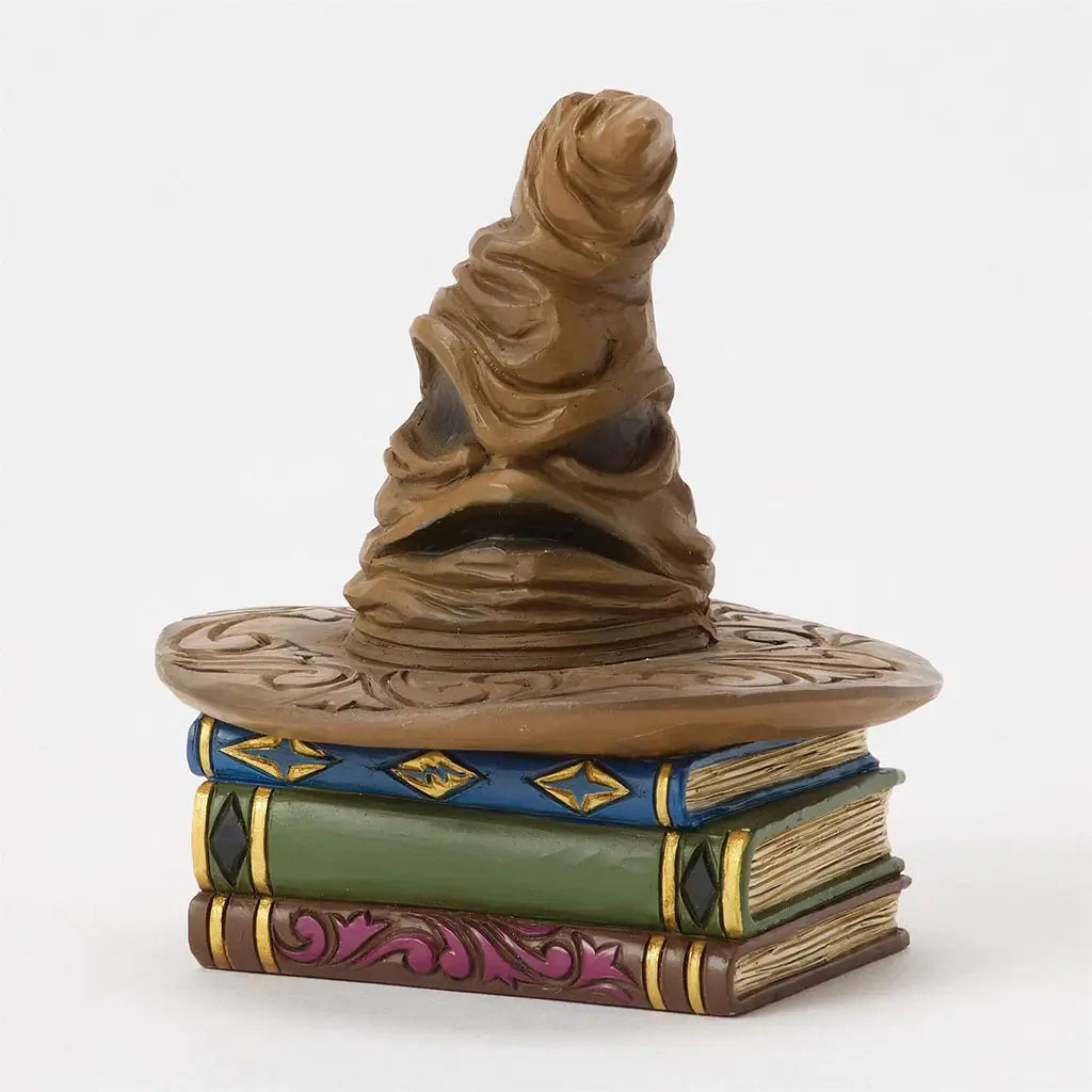 Front-facing Jim Shore Sorting Hat collectible shows iconic wizarding hat with carved brim, perched on three detailed magical books with ornate trim.