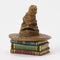 Front-facing Jim Shore Sorting Hat collectible shows iconic wizarding hat with carved brim, perched on three detailed magical books with ornate trim.