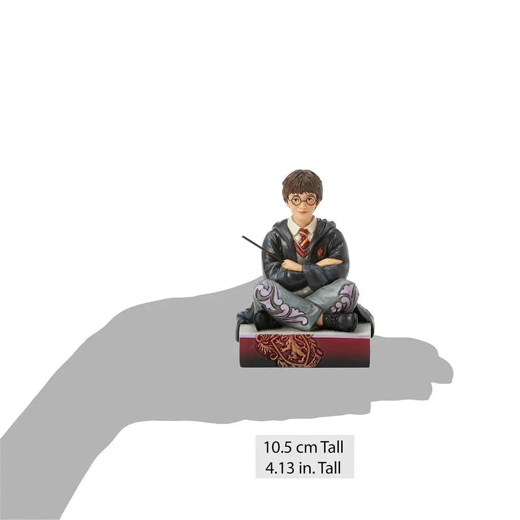 Jim Shore Harry Potter figurine displayed on a hand silhouette for scale, 10.5 cm tall, featuring Harry in Gryffindor robes holding a wand with folded arms.