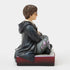 Left side view of Jim Shore Harry Potter figurine, painted in Hogwarts robes, holding a wand, seated on a decorative base with crest carving.