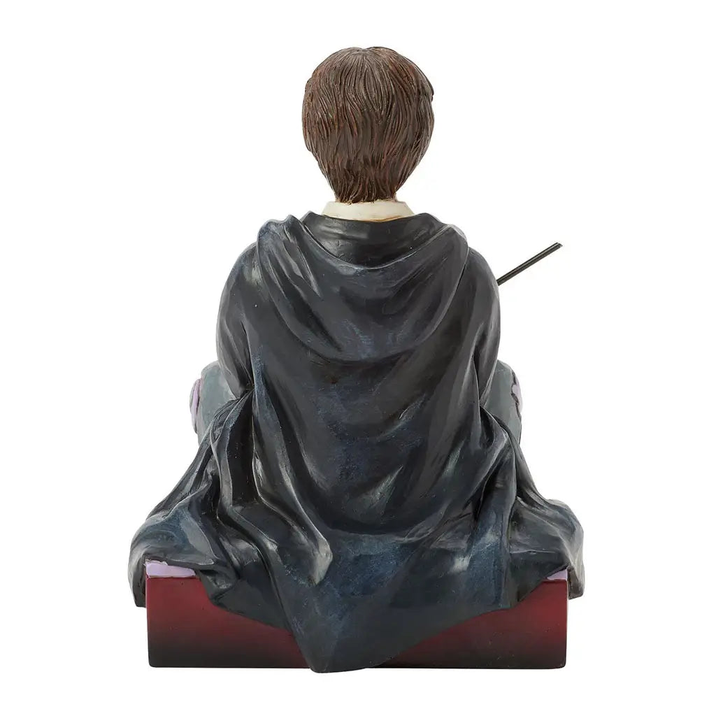 Rear view of Harry Potter figurine by Jim Shore, showing textured carved robe folds and short brown hair, sitting cross-legged on a maroon base.