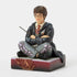 Right angled view of Jim Shore Harry Potter figurine, showing sculpted black robe folds, wand, and Gryffindor crest on decorative maroon base.
