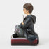Right side view of Jim Shore Harry Potter figurine, highlighting carved robe details, wand in hand, and seated pose atop maroon crest-adorned base.