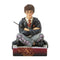 Front view of Jim Shore Harry Potter figurine, hand-painted with glasses, Gryffindor robes, and wand in hand, seated cross-legged on a base with crest details.