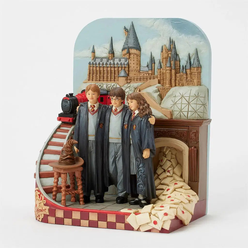 Right angled view of Harry Potter Jim Shore figurine featuring castle backdrop, Hogwarts Express, Gryffindor trio, Sorting Hat, fireplace, and overflowing letters.