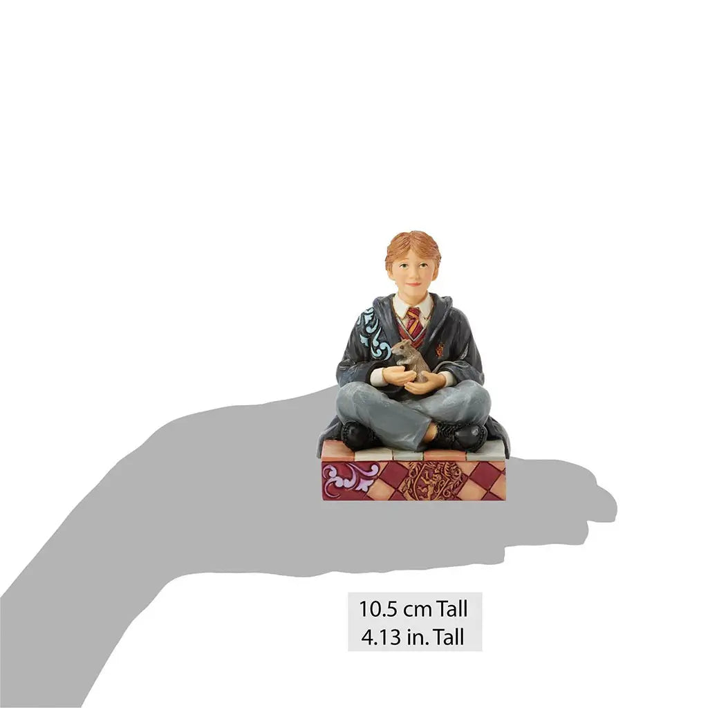 Jim Shore Ron Weasley figurine shown in hand silhouette for scale, standing 10.5 cm tall, hand-painted with Hogwarts robes and holding Scabbers the pet rat.