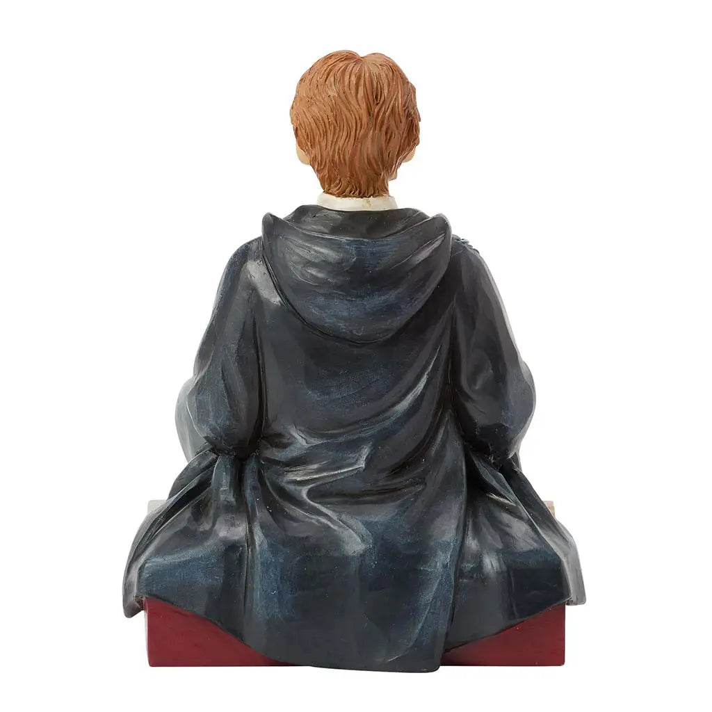Rear view of Jim Shore Ron Weasley figurine, highlighting textured carved folds of dark blue robes and reddish-brown hair, with maroon checkered base visible.