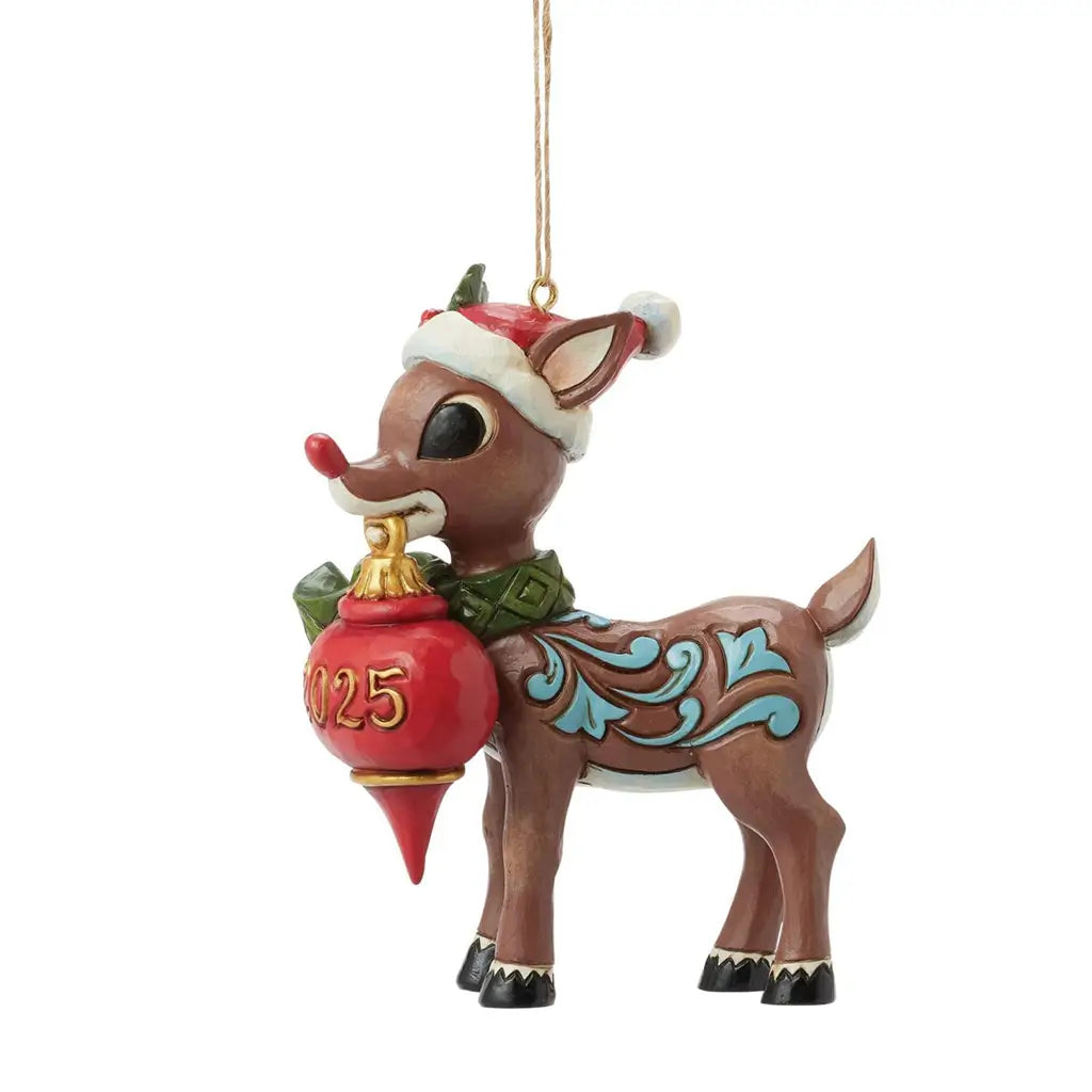 Side view of Jim Shore 2025 Rudolph the Red-Nosed Reindeer ornament, wearing Santa hat and green scarf, holding red ornament with gold numbers.