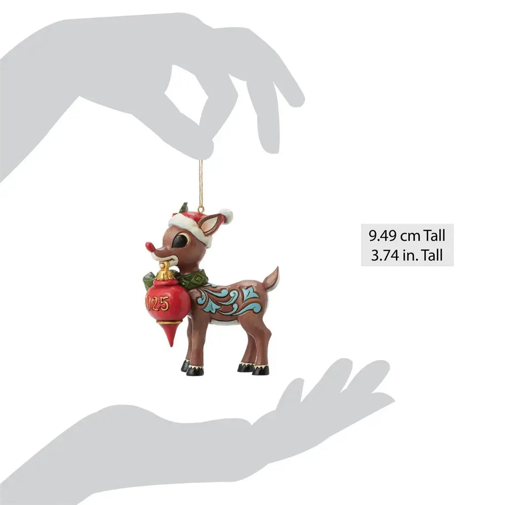 Scale view of Jim Shore 2025 Rudolph ornament, measuring 3.74 inches tall, with blue folk art swirls, green scarf, and red holiday ornament.
