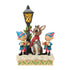 Jim Shore Christmas figurine of Rudolph and elves under a lamppost, hand-carved with folk art patterns, holly garlands, and snowy base, ideal for festive holiday displays.