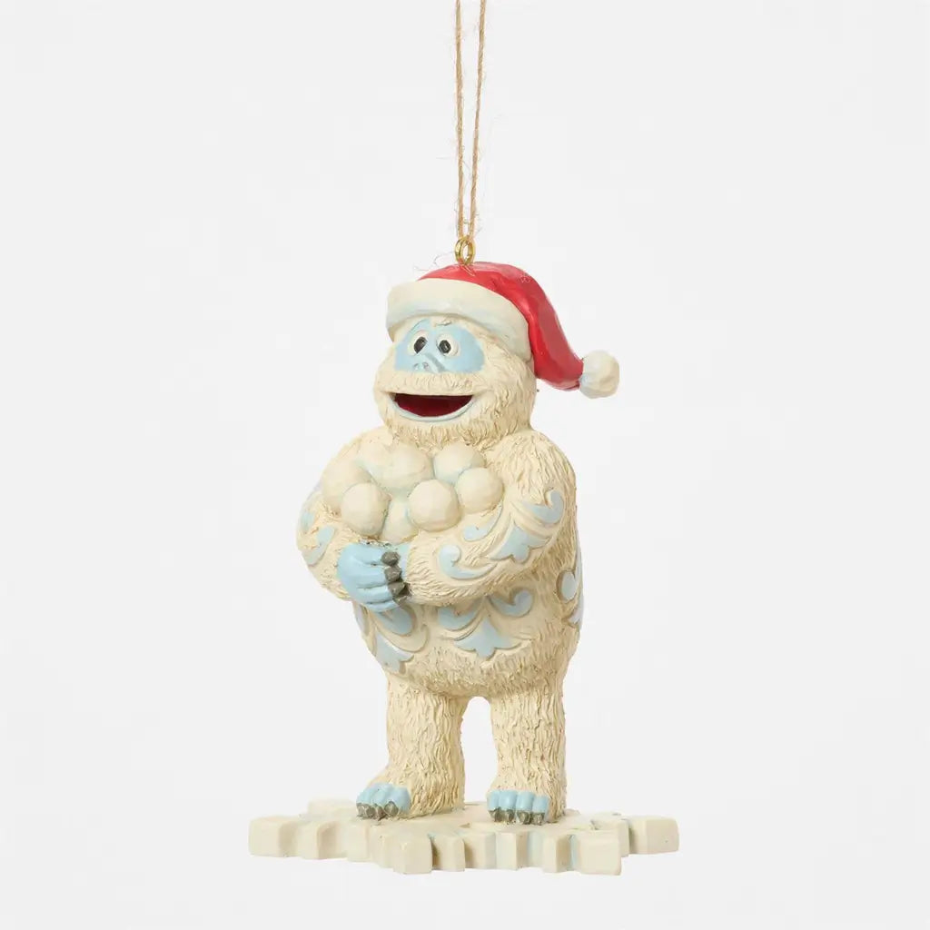 Three-quarter angle of Jim Shore Bumble ornament, holding snowballs with Santa hat and folk art detailing on snowy base.