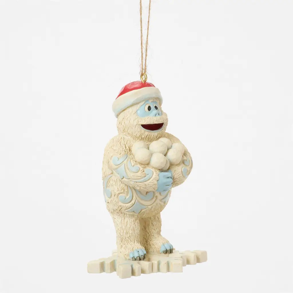 Angled view of Jim Shore Bumble holiday ornament, showing white textured fur, blue carved designs, and cheerful snowball pose.