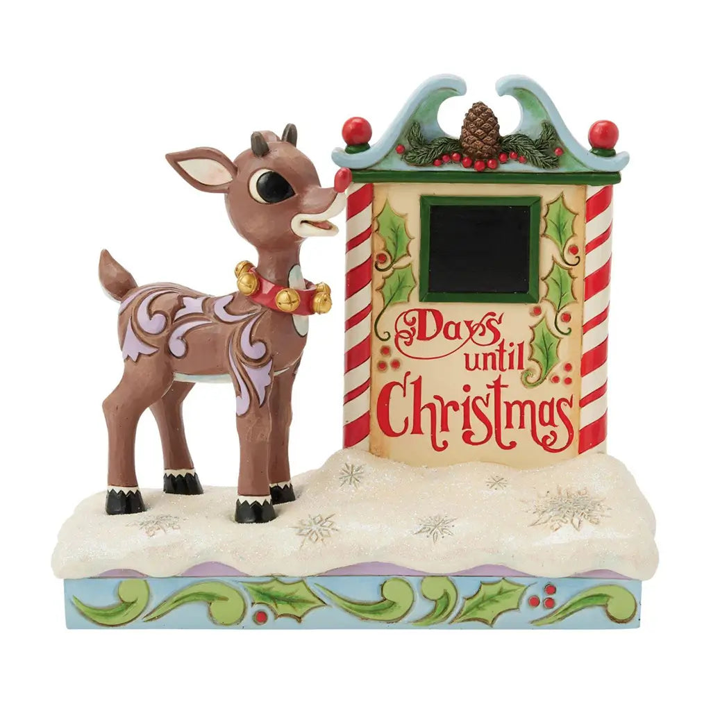 Front view of Jim Shore Rudolph Christmas countdown figurine, featuring 'Days Until Christmas' text, holly designs, pinecone topper, and glittery snow base.