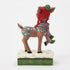 Brown reindeer figurine with ornate blue patterns, red knit hat, and purple scarf, standing on white snowflake base with green woven trim, viewed from the back.