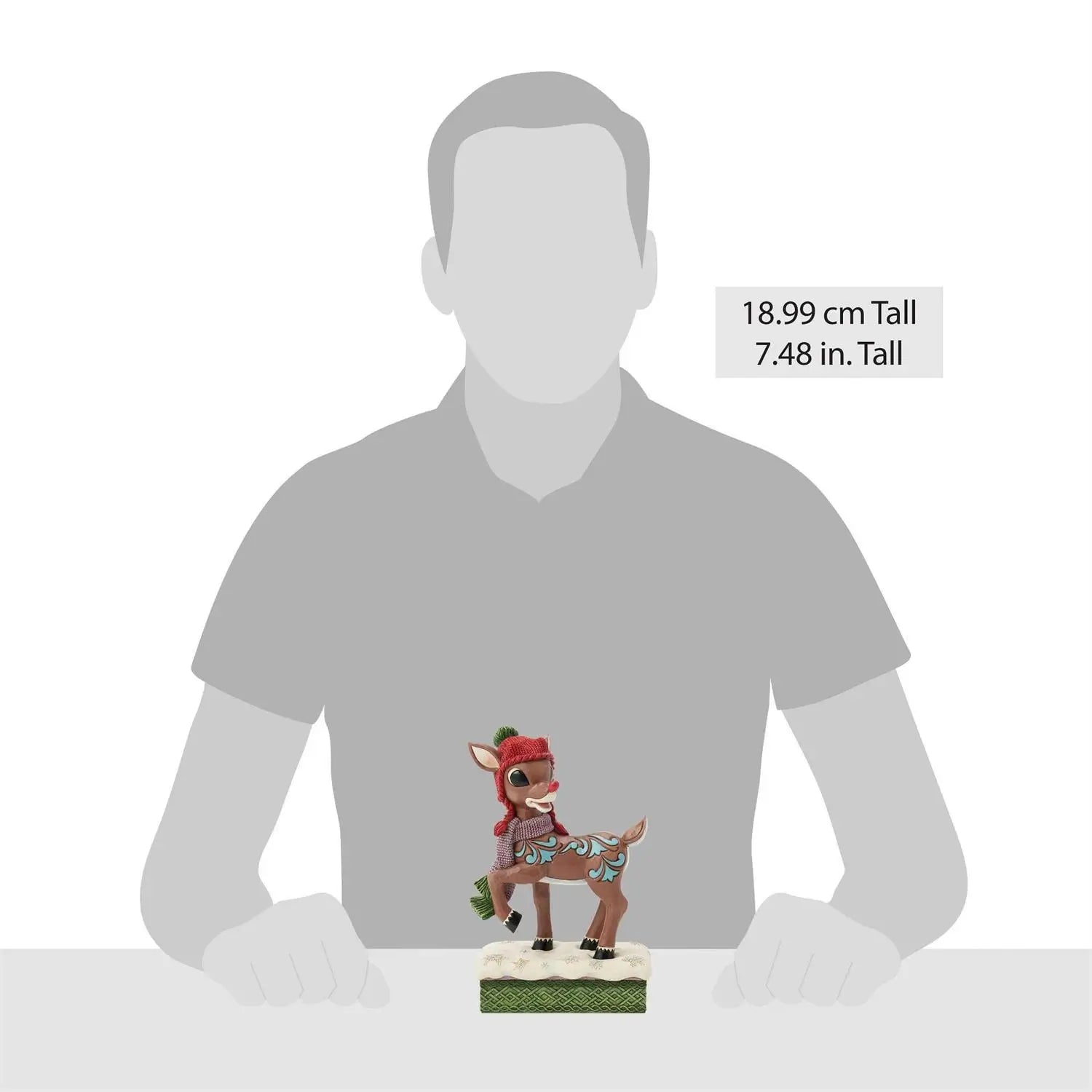 Hand-painted Rudolph figurine in red knit hat and purple scarf with green ends, standing on snowy base; shown beside scale silhouette, measuring 7.48 inches tall.