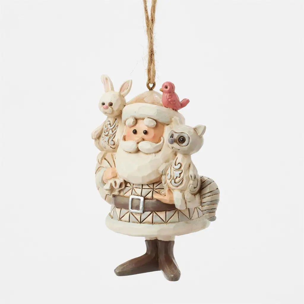 Jim Shore Santa ornament in cream tones with patterned coat, holding bunny and raccoon, red bird on hat, sack on back, shown at angled view against white.