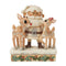 Front view of Jim Shore cream Santa figurine with white beard, hugging two reindeer, one with red nose, on snow base trimmed with holly leaves and pinecones.
