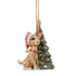 Angled front view of Jim Shore woodland Rudolph ornament beside Christmas tree with red ornaments.