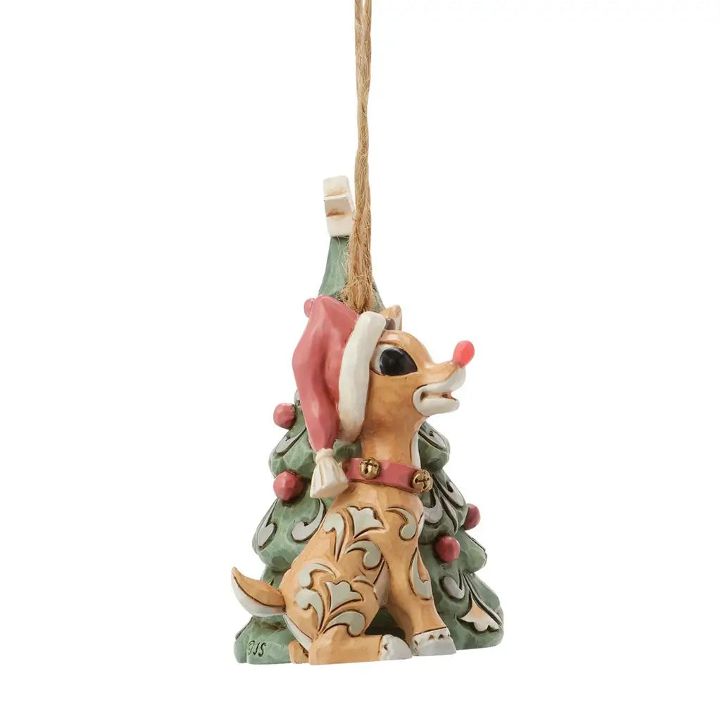 Side view of Jim Shore woodland Rudolph ornament next to Christmas tree, showing carved folk art patterns.
