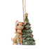 Front view of Jim Shore woodland Rudolph ornament wearing Santa hat and sitting beside decorated Christmas tree.